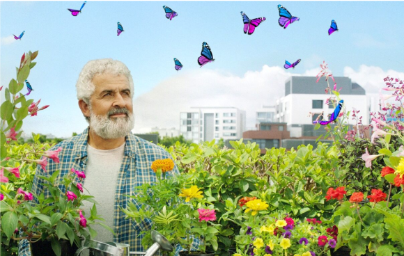 An older man with a white beard and white hair standing in a garden of colourful
